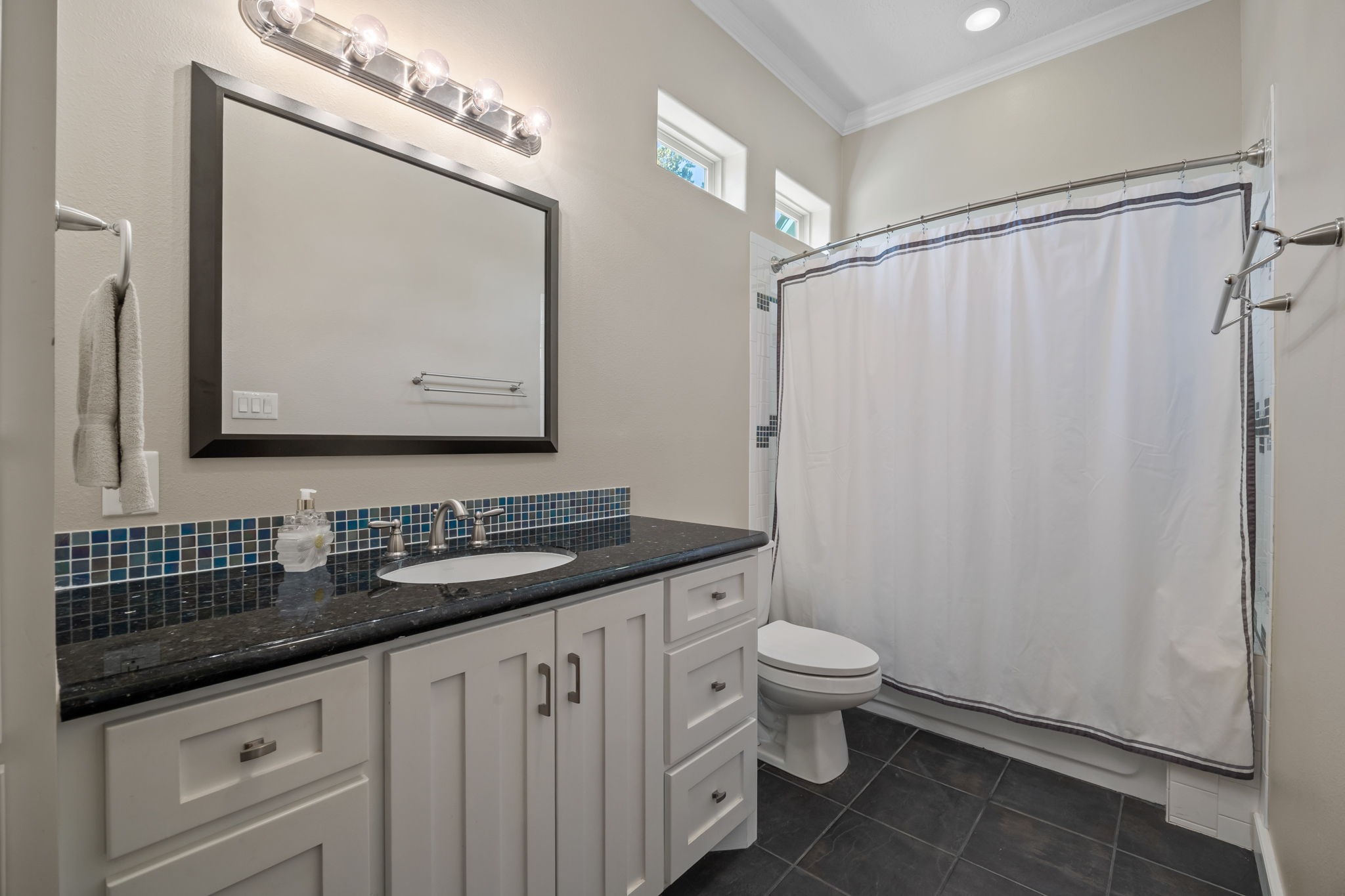 3998 County Road 612 Angleton, TX 77515 - Photo 31 of 47 a bathroom with a granite countertop sink a toilet a mirror and shower curtain
