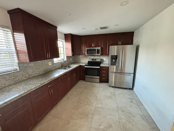 a kitchen with stainless steel appliances granite countertop a refrigerator sink and stove