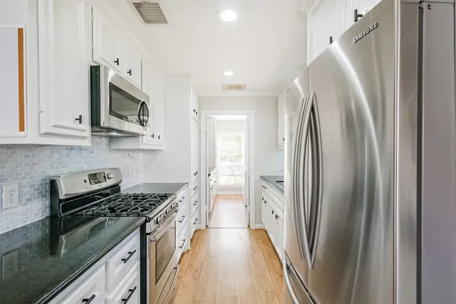 a kitchen with stainless steel appliances granite countertop a refrigerator a stove and a sink