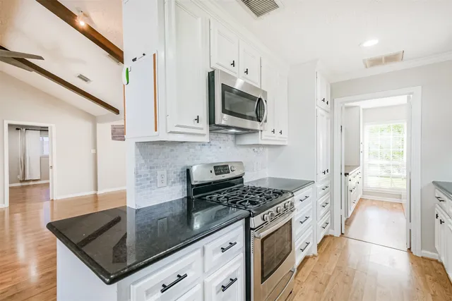 a kitchen with stainless steel appliances granite countertop a stove a sink and a microwave