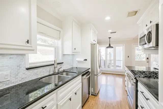 a kitchen with granite countertop a sink stainless steel appliances and cabinets