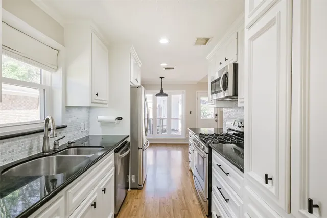 a kitchen with granite countertop a sink stove refrigerator and cabinets