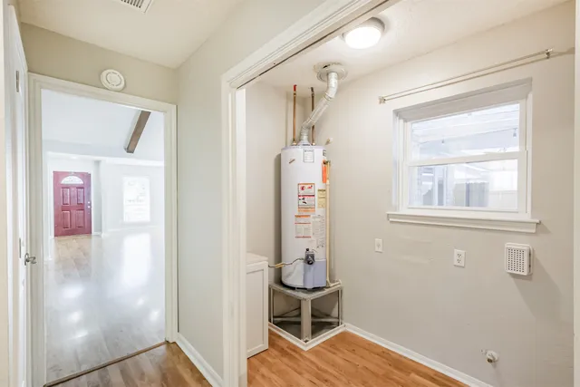 a view of an empty room with wooden floor and a ceiling fan
