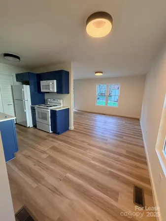 a view of kitchen and empty room with wooden floor