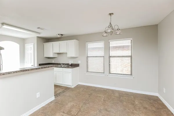 a kitchen with granite countertop white cabinets and window