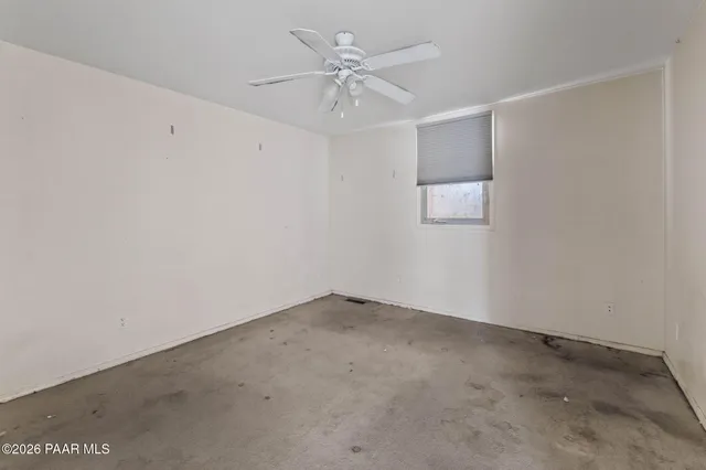 an empty room with chandelier fan and windows
