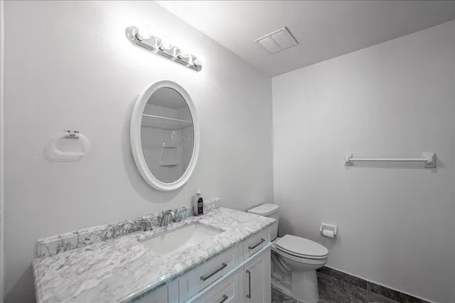 a bathroom with a granite countertop sink a mirror and a toilet