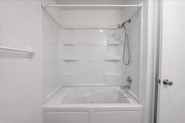 a white bath tub sitting next to a shower