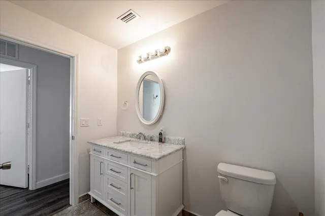 a bathroom with a granite countertop toilet a sink and a mirror