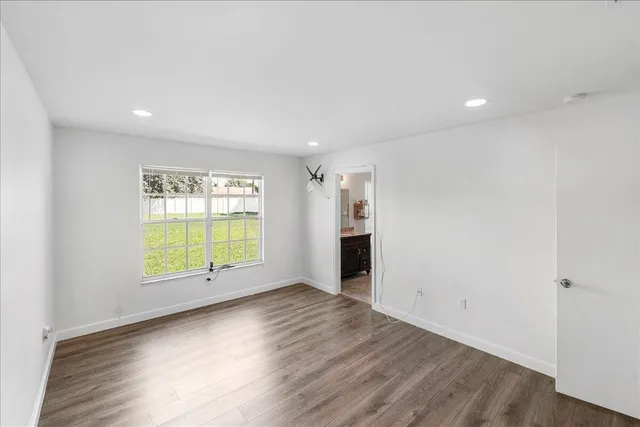 a view of an empty room with a window and wooden floor