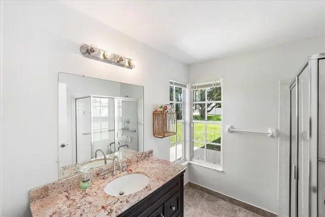 a bathroom with a granite countertop sink a mirror and a shower