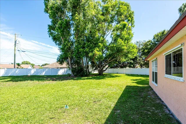 a view of a swimming pool with a yard and large trees