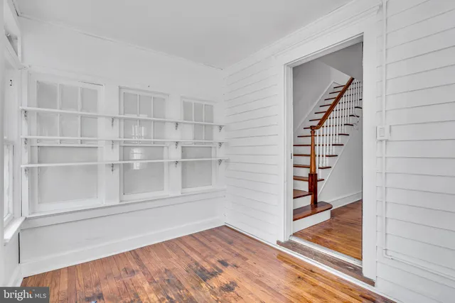 a view of an empty room with stairs and wooden floor