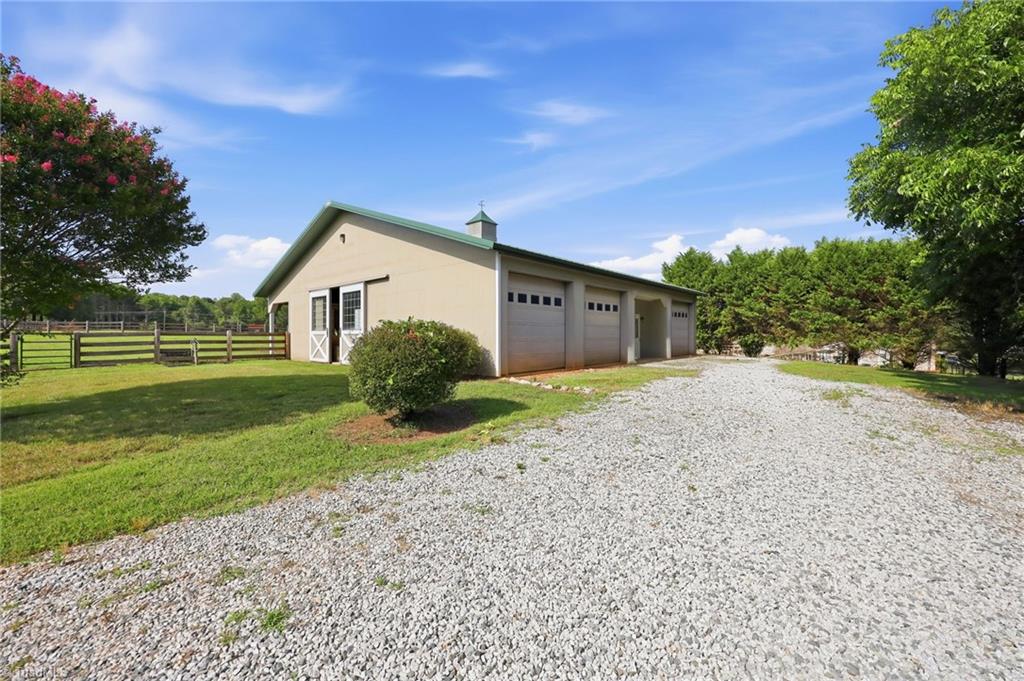 8861 Boylston Road Colfax, NC 27235 - Photo 3 of 50 The impressive Morton barn is thoughtfully designed for both equestrian and hobby use, featuring three horse stalls, equipment bays, a heated workshop, tack room, hot water, and direct access to the fenced pasture and riding arena.