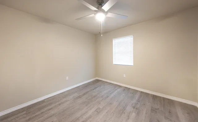 an empty room with a window and a fan