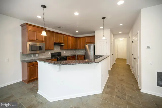 a kitchen with stainless steel appliances granite countertop a sink a stove a refrigerator a washer and dryer