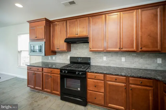 a kitchen with granite countertop a refrigerator stove and cabinets