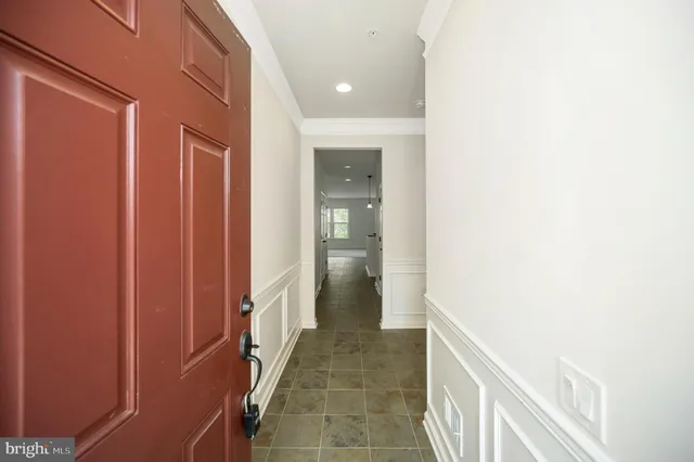 a view of a hallway with wooden floor and a bathroom