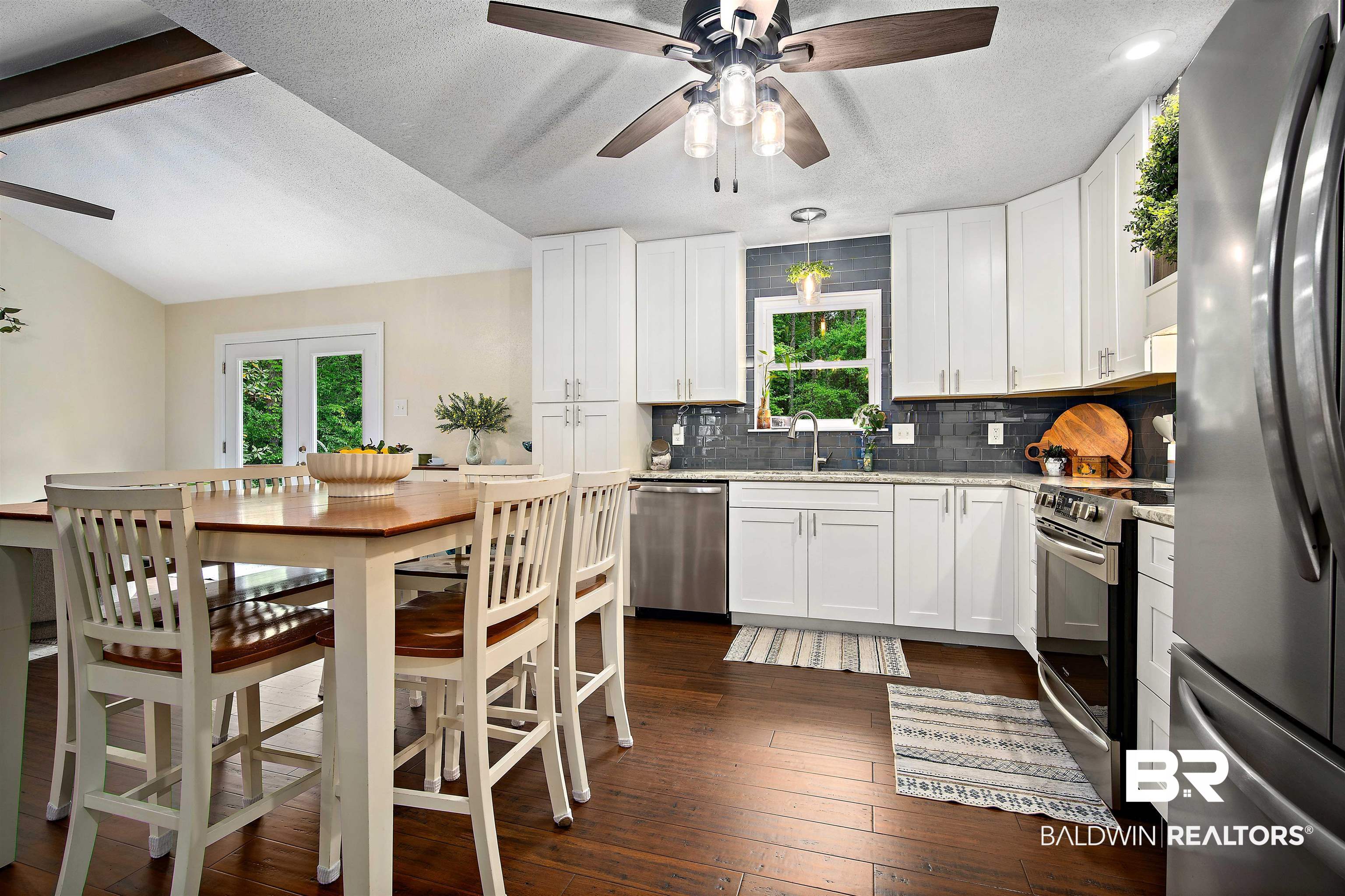 71 Caisson Trace Daphne, AL 36527 - Photo 12 of 36 Open-concept kitchen with wood-finish flooring, white cabinetry, dark subway tile backsplash, and stainless steel appliances