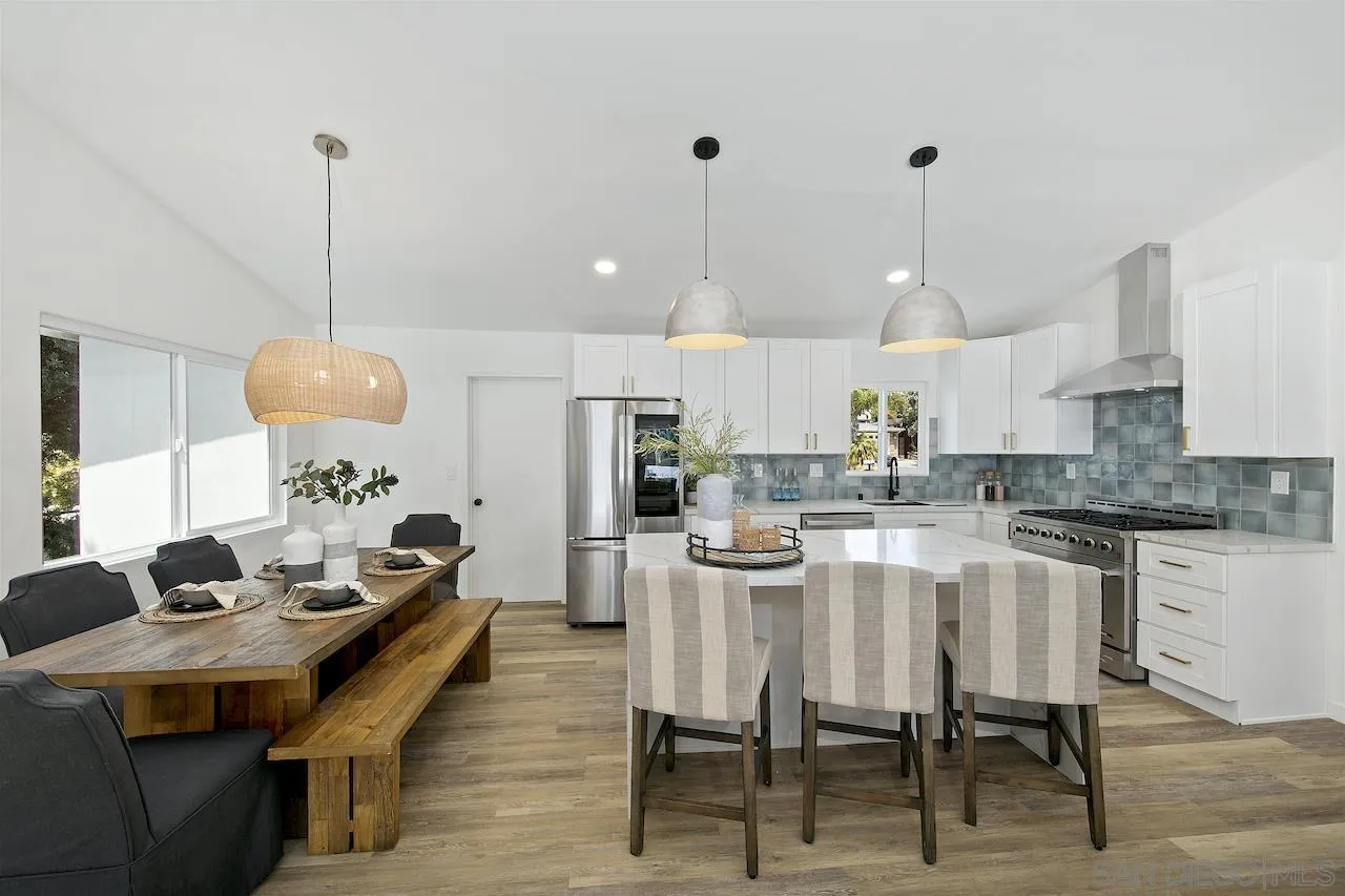 725 Cathy Lane Encinitas, CA 92007 - Photo 7 of 31 a kitchen with stainless steel appliances kitchen island granite countertop a table chairs and a wooden floor