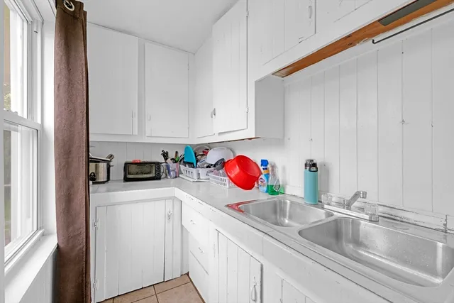 a kitchen with granite countertop a sink dishwasher and white cabinets