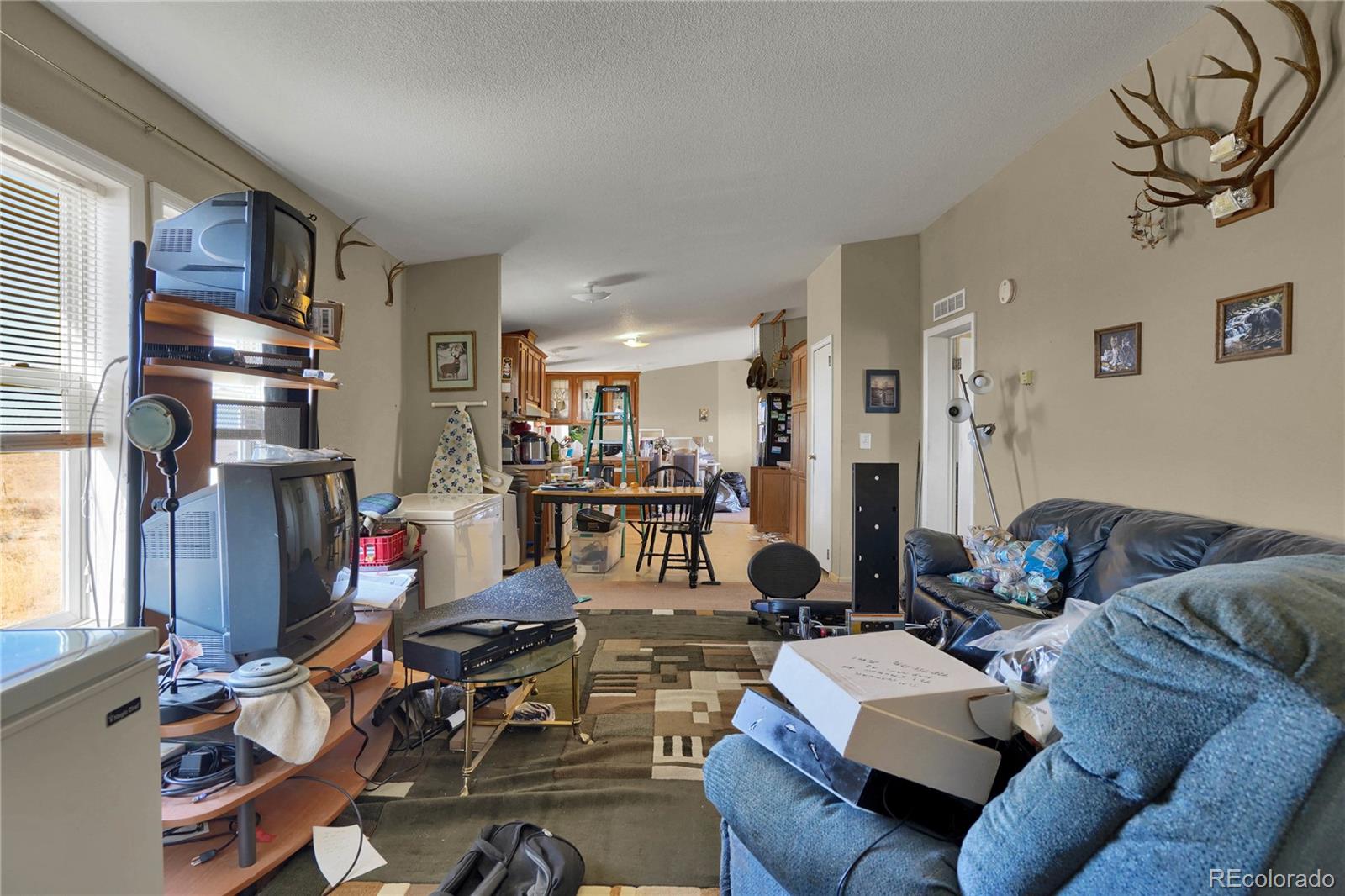 15840 South Lauppe Road Yoder, CO 80864 - Photo 10 of 22 a living room with furniture a flat screen tv and floor to ceiling window