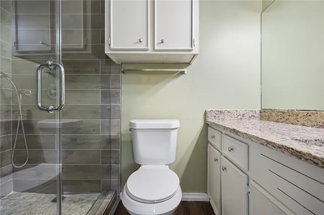 a bathroom with a granite countertop toilet a sink and shower