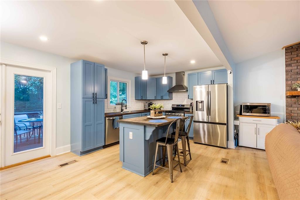 6375 Caladium Drive Acworth, GA 30102 - Photo 13 of 41 a kitchen with stainless steel appliances kitchen island granite countertop a refrigerator a stove a sink a dining table and chairs with wooden floor