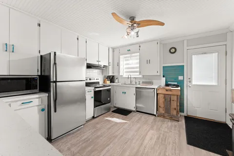 a kitchen with a refrigerator wooden floor and white cabinets