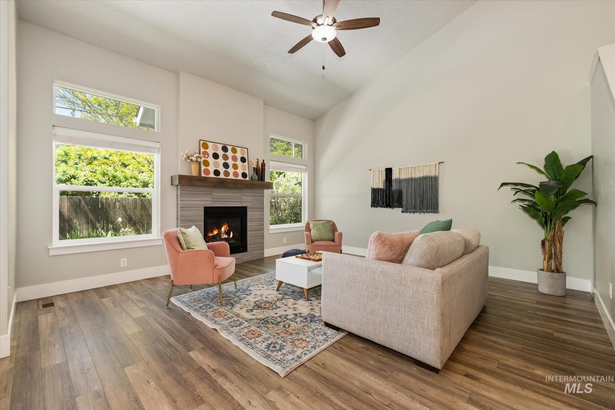 1915 South High Street Boise, ID 83706 - Photo 11 of 44 Vaulted living room featuring wood-finish flooring, a tiled fireplace with a wood mantle, and a ceiling fan