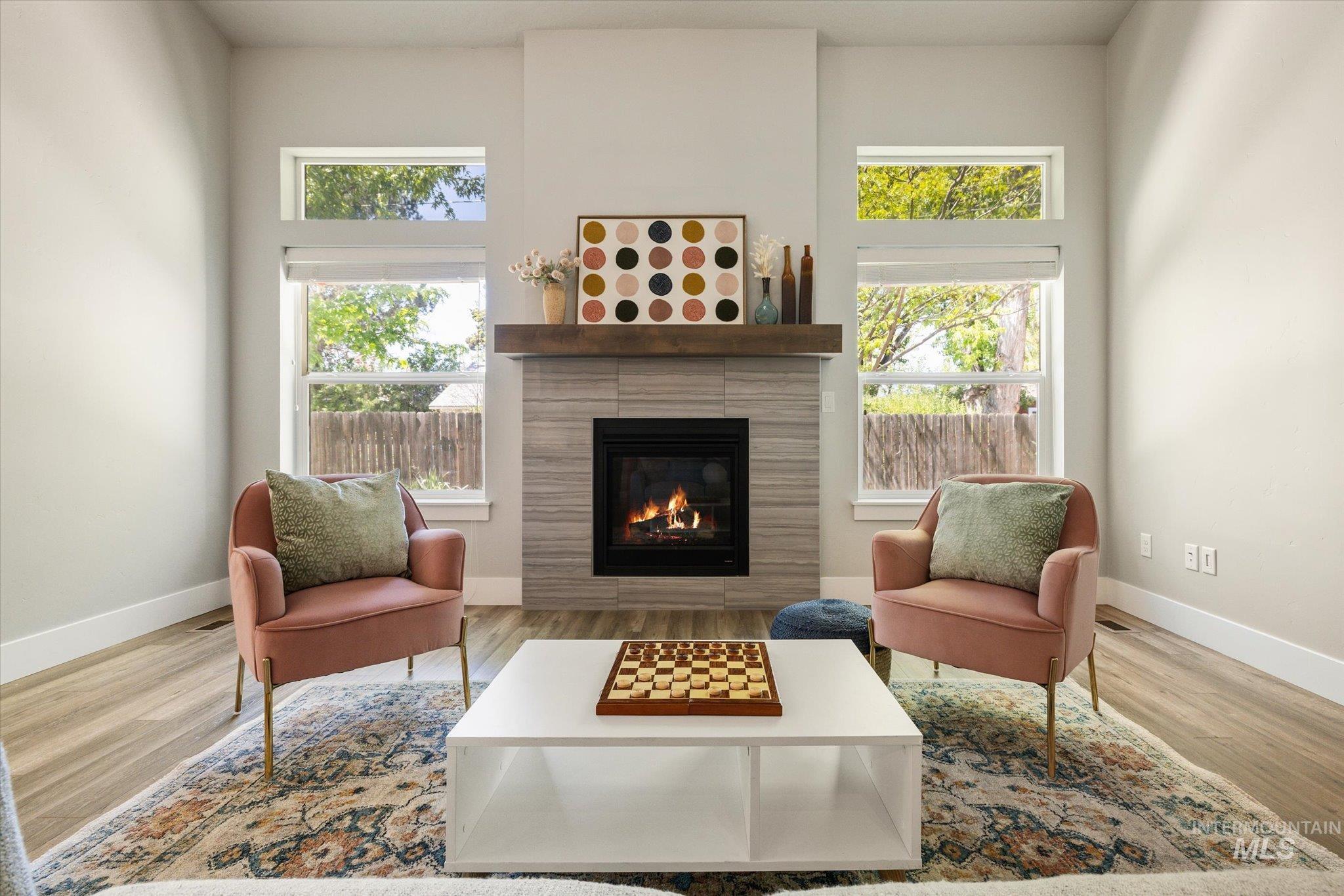 1915 South High Street Boise, ID 83706 - Photo 13 of 44 Living area featuring a tiled fireplace with a wood mantle, complemented by light-toned walls and wood-finish flooring
