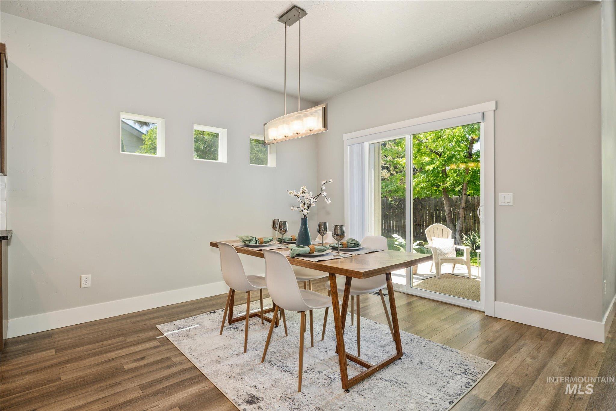 1915 South High Street Boise, ID 83706 - Photo 14 of 44 Bright dining space featuring wood-finish flooring, a contemporary linear chandelier, and three high-set square windows