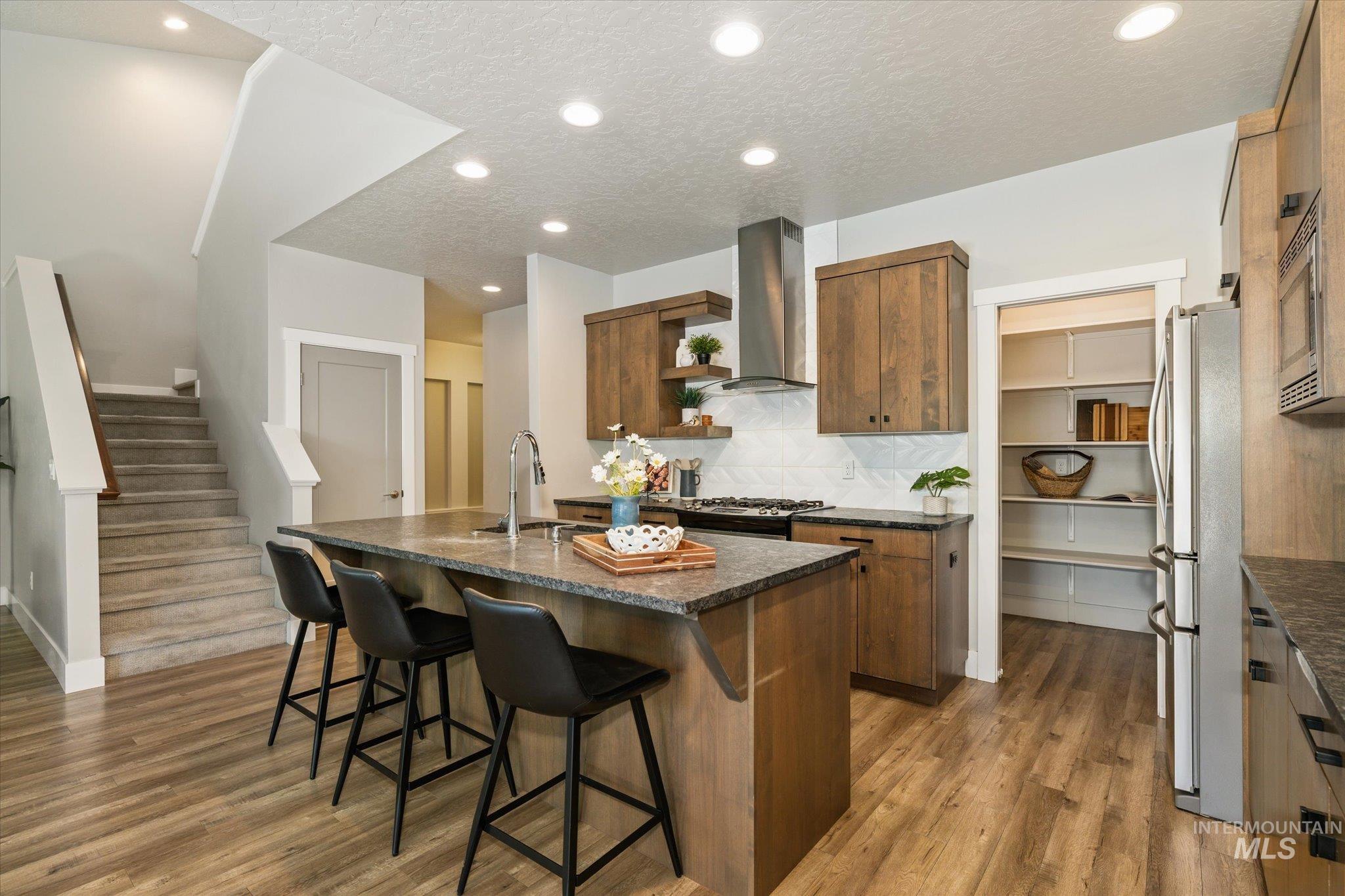 1915 South High Street Boise, ID 83706 - Photo 20 of 44 Kitchen featuring a large island with an undermount sink, wood-finish flooring, recessed lighting, a built-in pantry with shelving, and light wood cabinetry