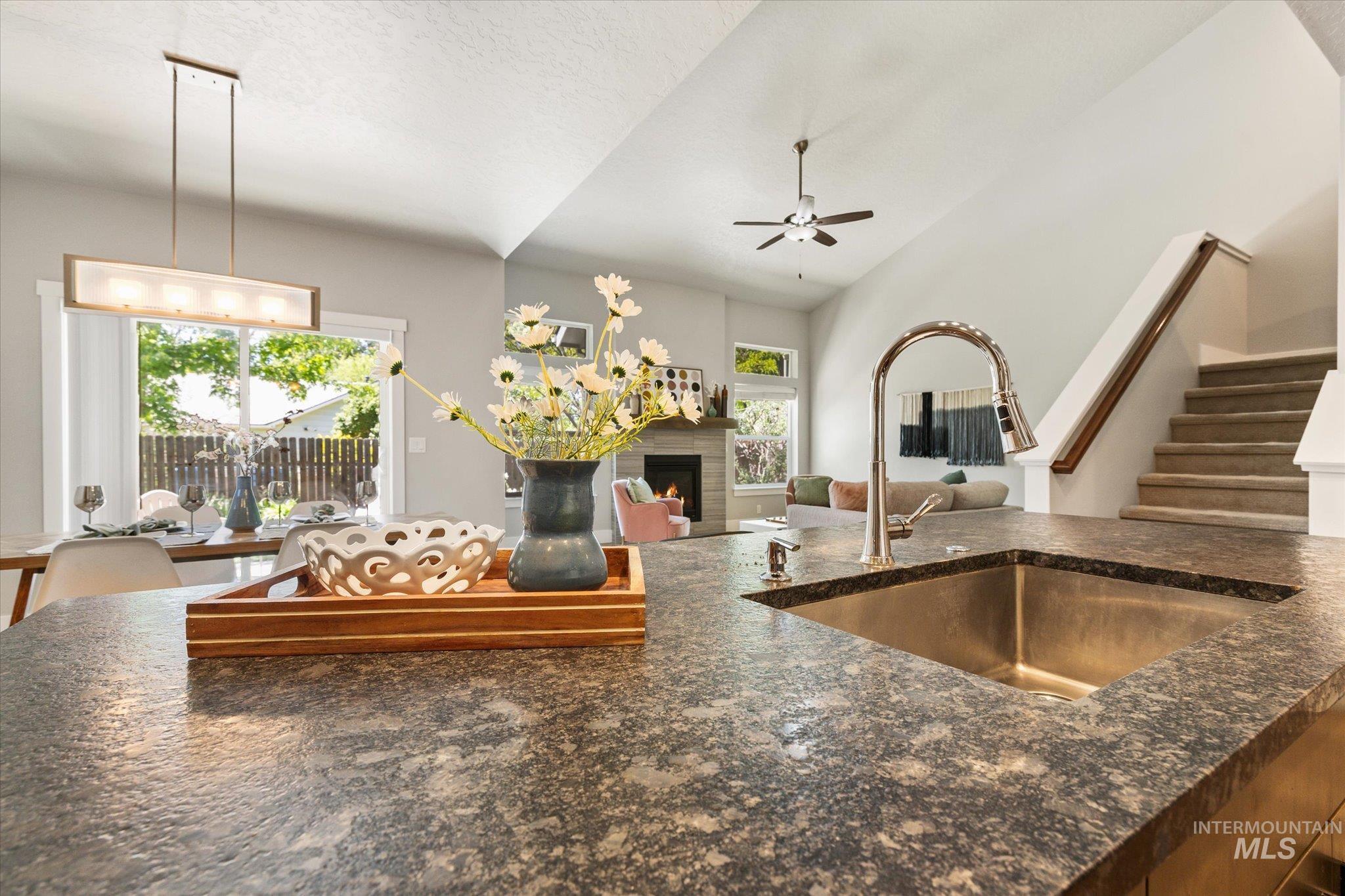 1915 South High Street Boise, ID 83706 - Photo 24 of 44 Kitchen island featuring a stainless steel sink with a high-arch faucet, speckled countertop, and integrated breakfast bar