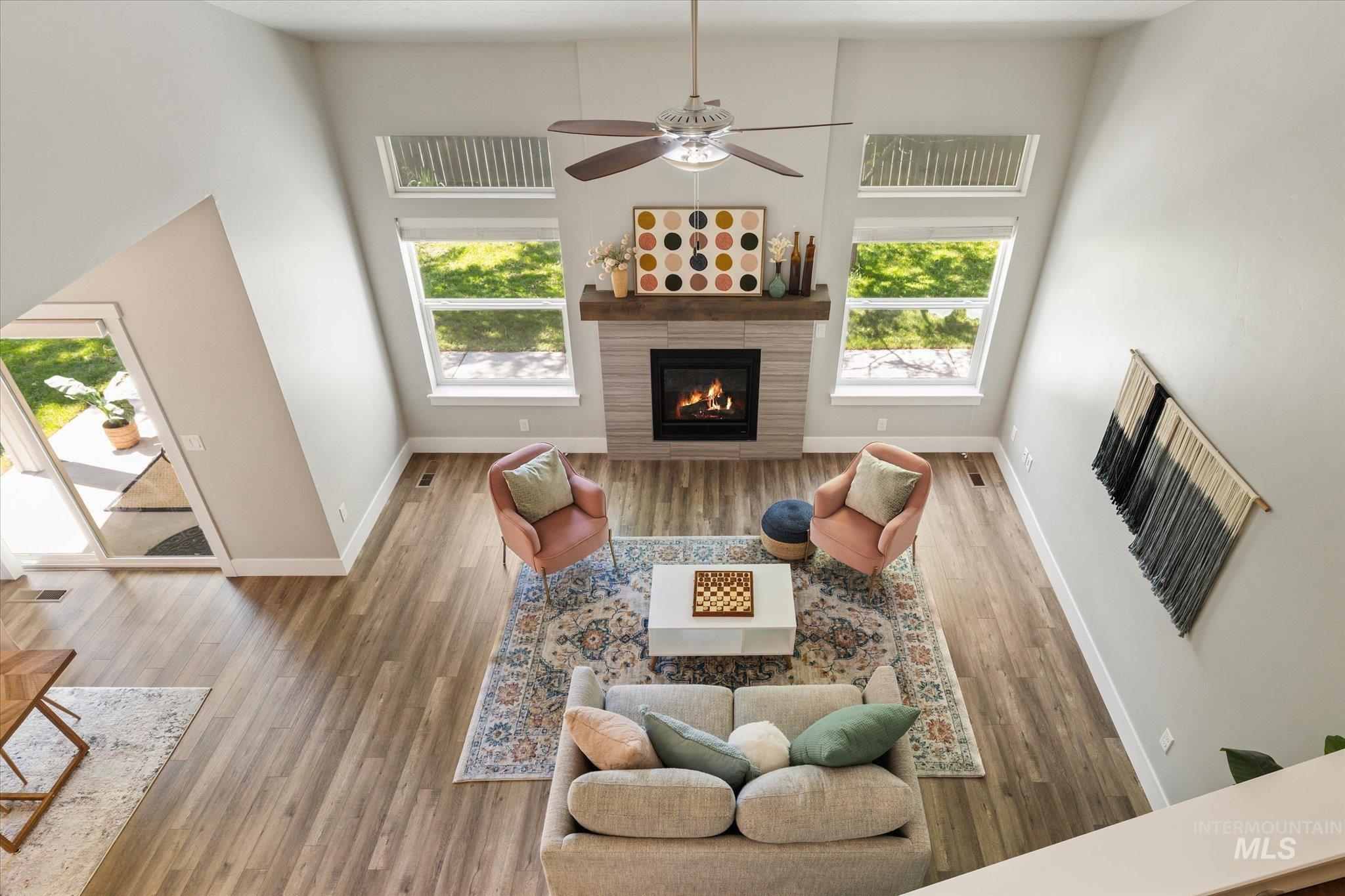 1915 South High Street Boise, ID 83706 - Photo 28 of 44 Vaulted ceiling living room featuring wood-finish flooring, a contemporary fireplace with a timber mantel, and multiple windows providing ambient light