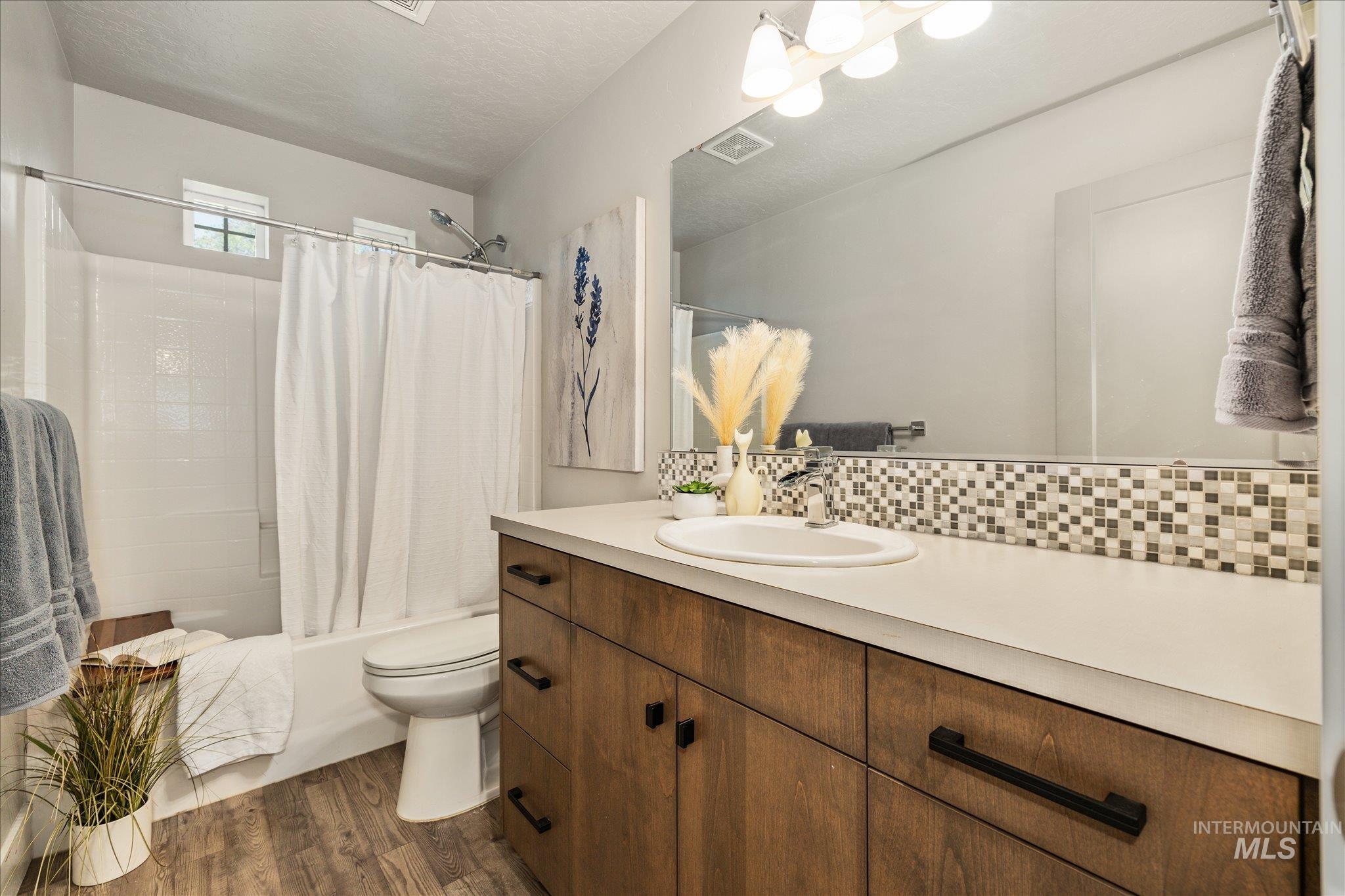 1915 South High Street Boise, ID 83706 - Photo 31 of 44 Bathroom featuring a single vanity with wood-finish cabinetry, a light-colored countertop, and a mosaic tile backsplash