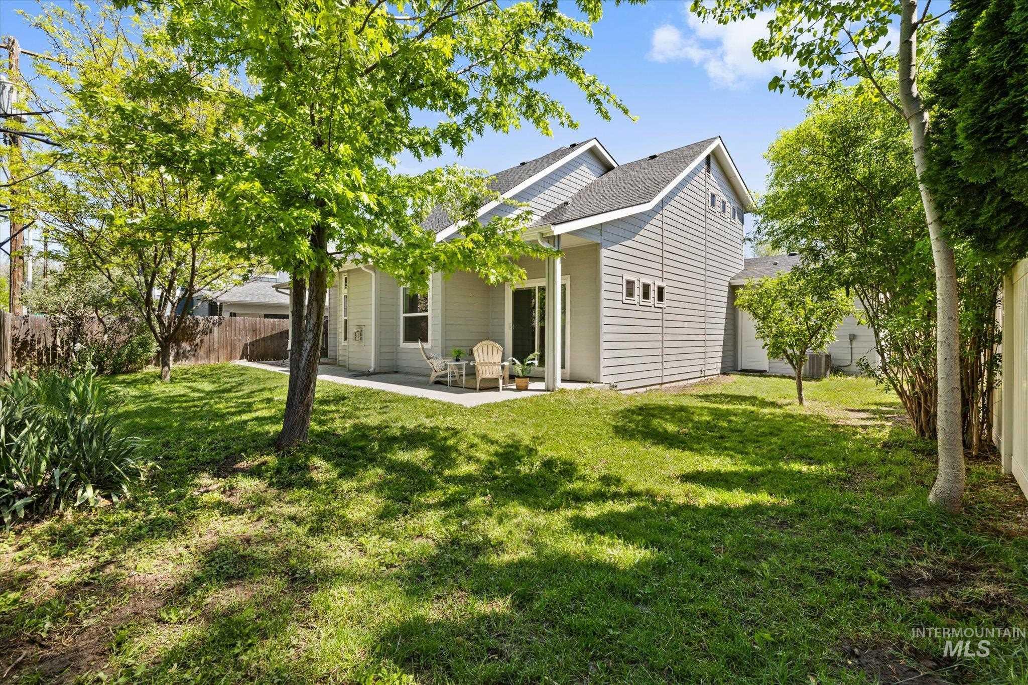 1915 South High Street Boise, ID 83706 - Photo 34 of 44 Spacious backyard with a grey siding exterior, a patio area, mature trees, and a dark shingle roof