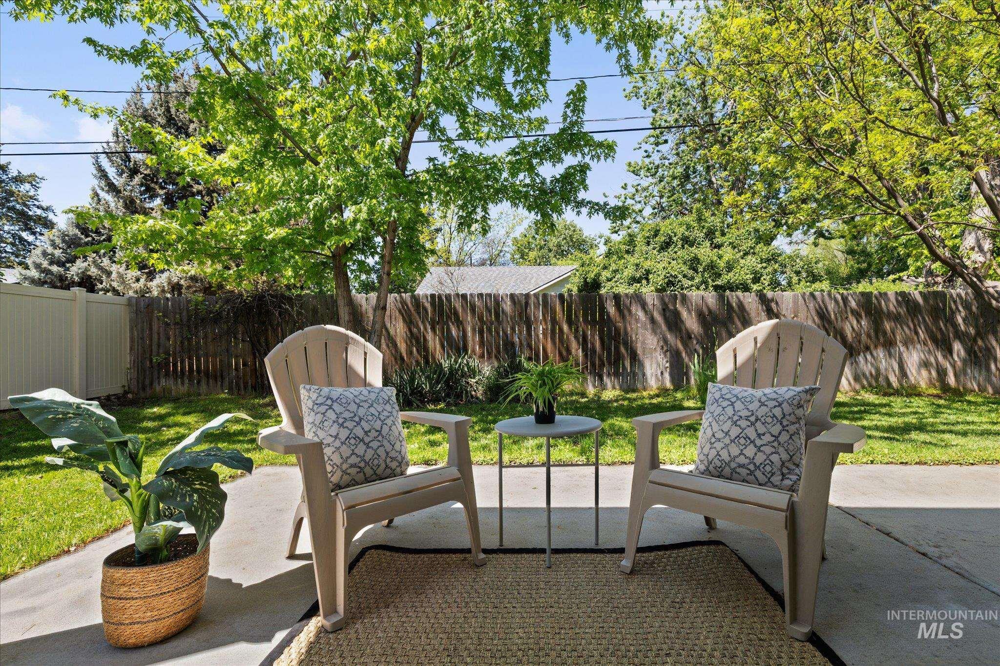 1915 South High Street Boise, ID 83706 - Photo 37 of 44 Concrete patio with an outdoor rug, surrounded by a lush lawn and mature trees