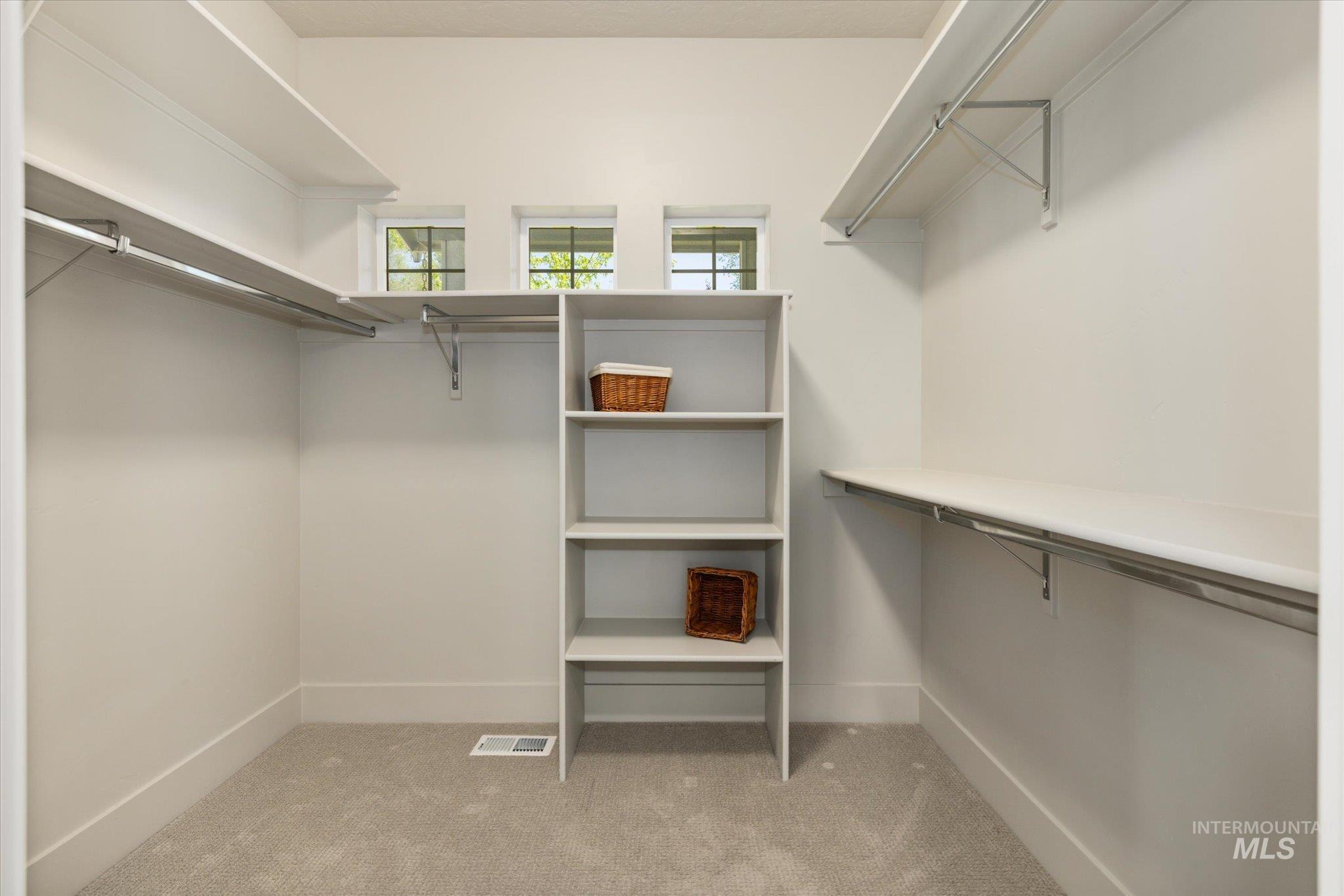 1915 South High Street Boise, ID 83706 - Photo 8 of 44 Spacious walk-in closet featuring light gray carpeting, multiple shelving units, integrated hanging rods, and three small transom windows providing natural light