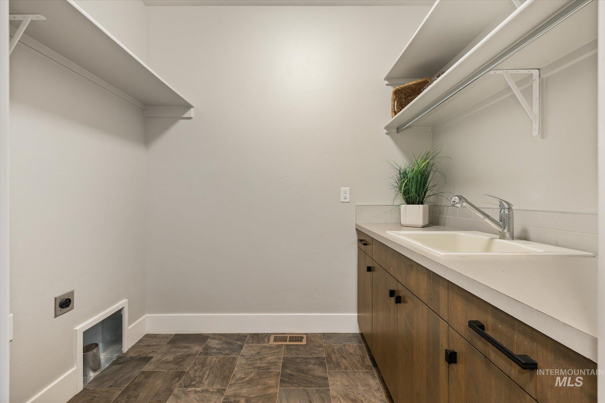1915 South High Street Boise, ID 83706 - Photo 9 of 44 Utility room featuring built-in shelving, wood-finish cabinetry with black hardware, an integrated sink, and tiled flooring