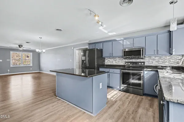 a kitchen with granite countertop a refrigerator and a stove top oven