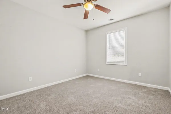an empty room with a window and a fan