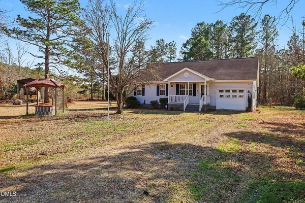 a front view of a house with a yard covered with snow and trees