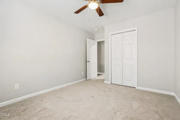 an empty room with ceiling fan and window