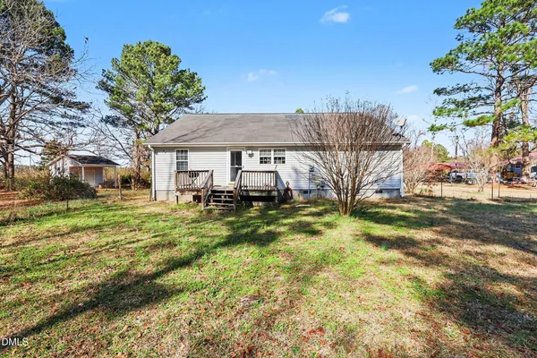 a view of a house with a big yard plants and large trees