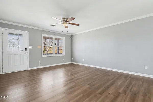 an empty room with wooden floor chandelier fan and windows