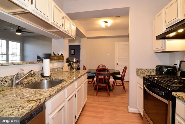 a kitchen with stainless steel appliances granite countertop a sink a stove and a wooden floors