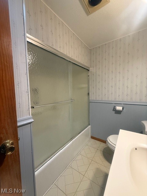 3804 Mahoning Road Northeast Canton, OH 44705 - Photo 18 of 22 Full bathroom featuring baseboards, wallpapered walls, tile patterned floors, toilet, and bath / shower combo with glass door