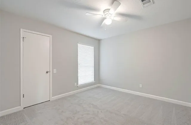 an empty room with a window and a fan
