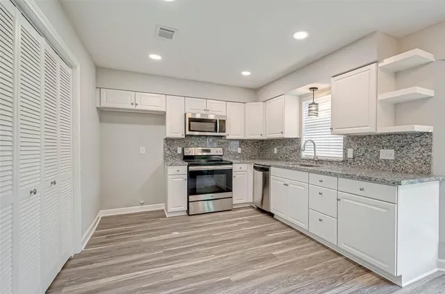 a kitchen with granite countertop white cabinets and stainless steel appliances